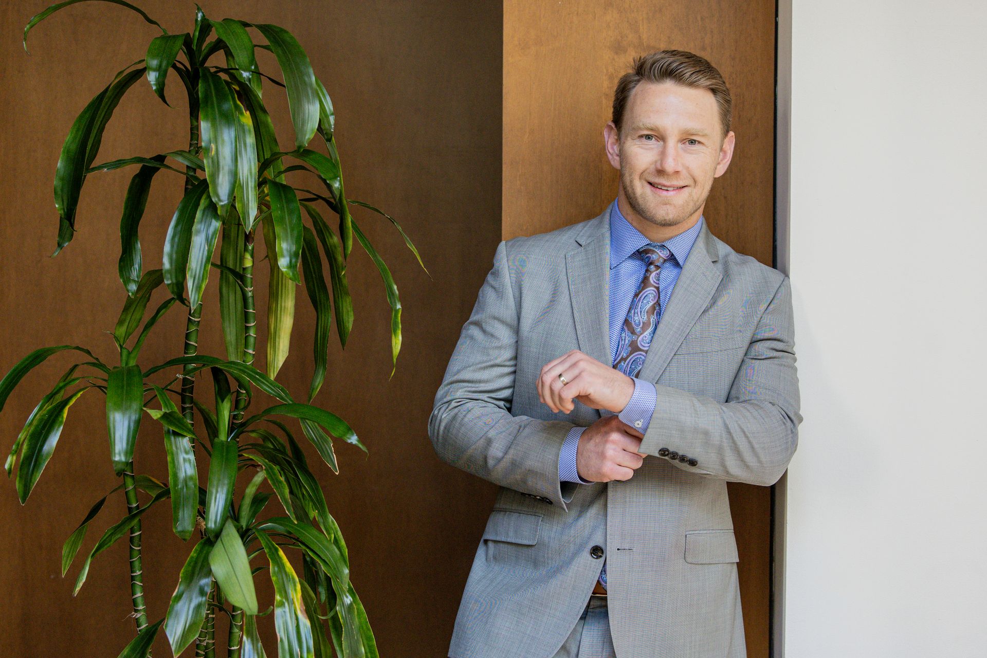 Aaron Steigerwalt leaning against a wall next to a plant