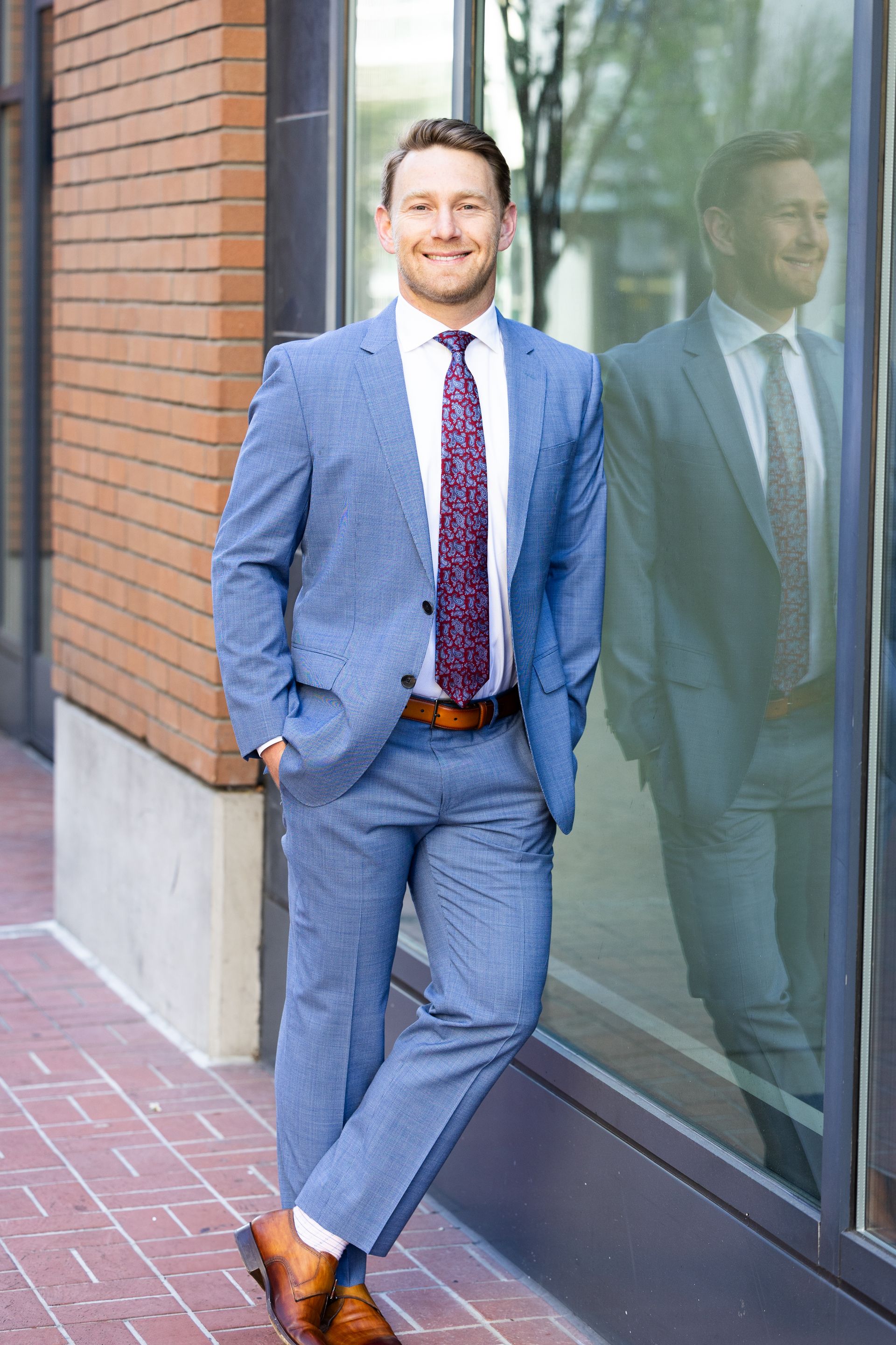 Attorney Aaron Steigerwalt leaning against a window outside a brick building on a brick sidewalk